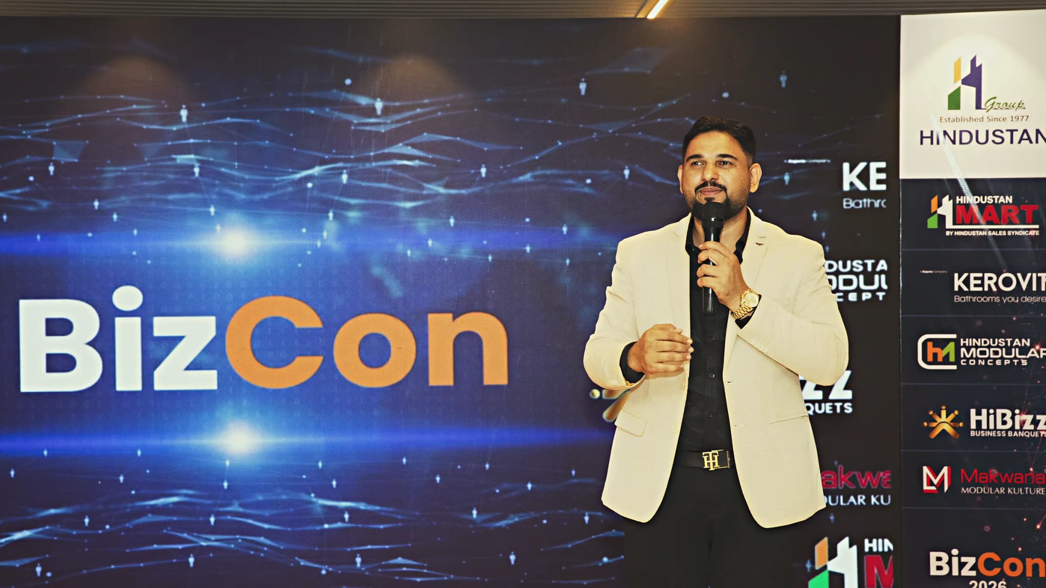 Speaker presenting on the HiBizz stage in Goa in front of a full-width LED backdrop